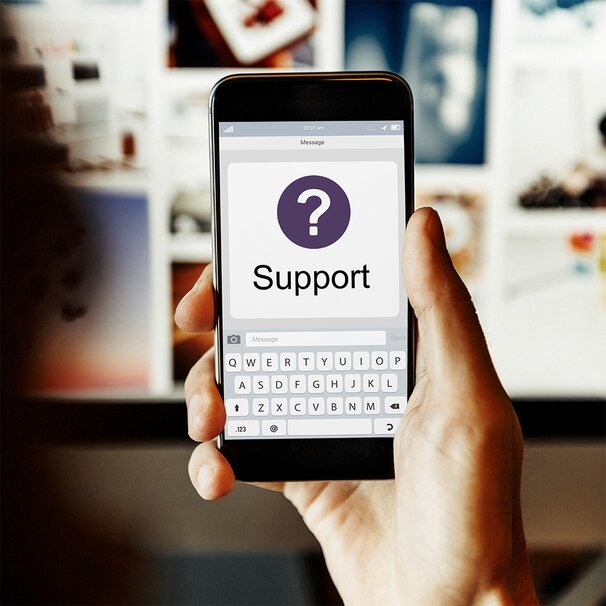 Hand holding a smartphone with a Support message on screen, representing OnlyFans chatting support