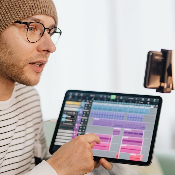 OnlyFans content creator pointing at a color-coded timeline on a tablet next to a phone set up for filming